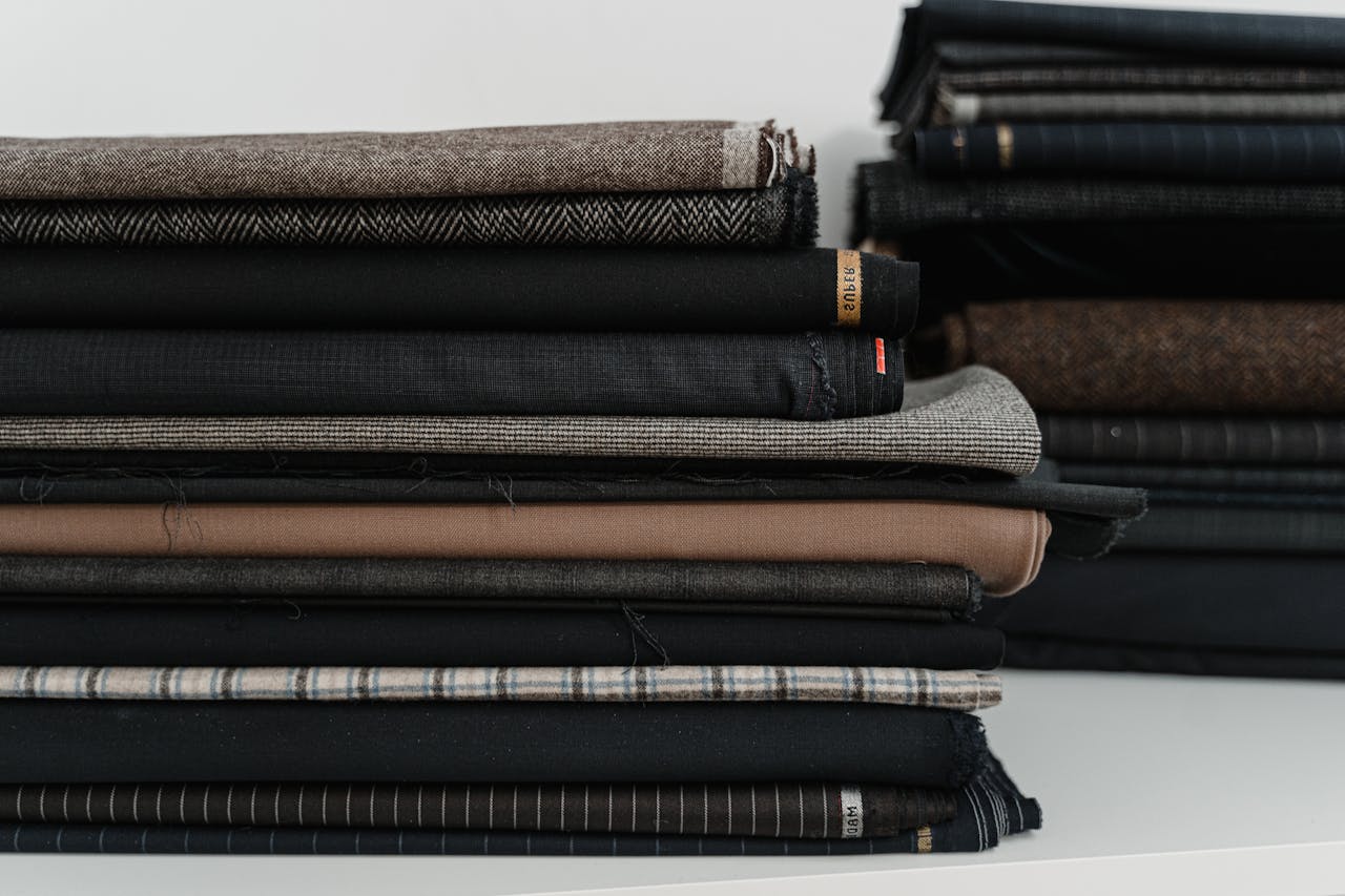 A neatly arranged pile of diverse fabrics, ideal for a fashion designer or tailor's workshop.